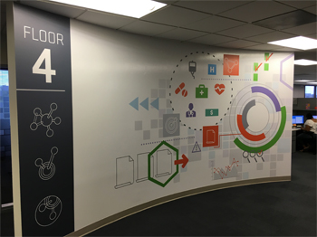 Fourth floor entrance graphic on curved wall featuring the new HMS colors and icons