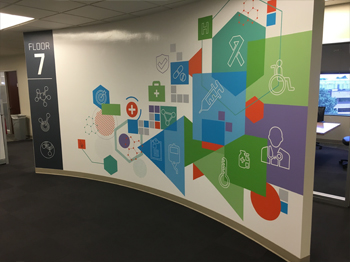 Seventh floor entrance graphic on curved wall featuring the new HMS colors and icons